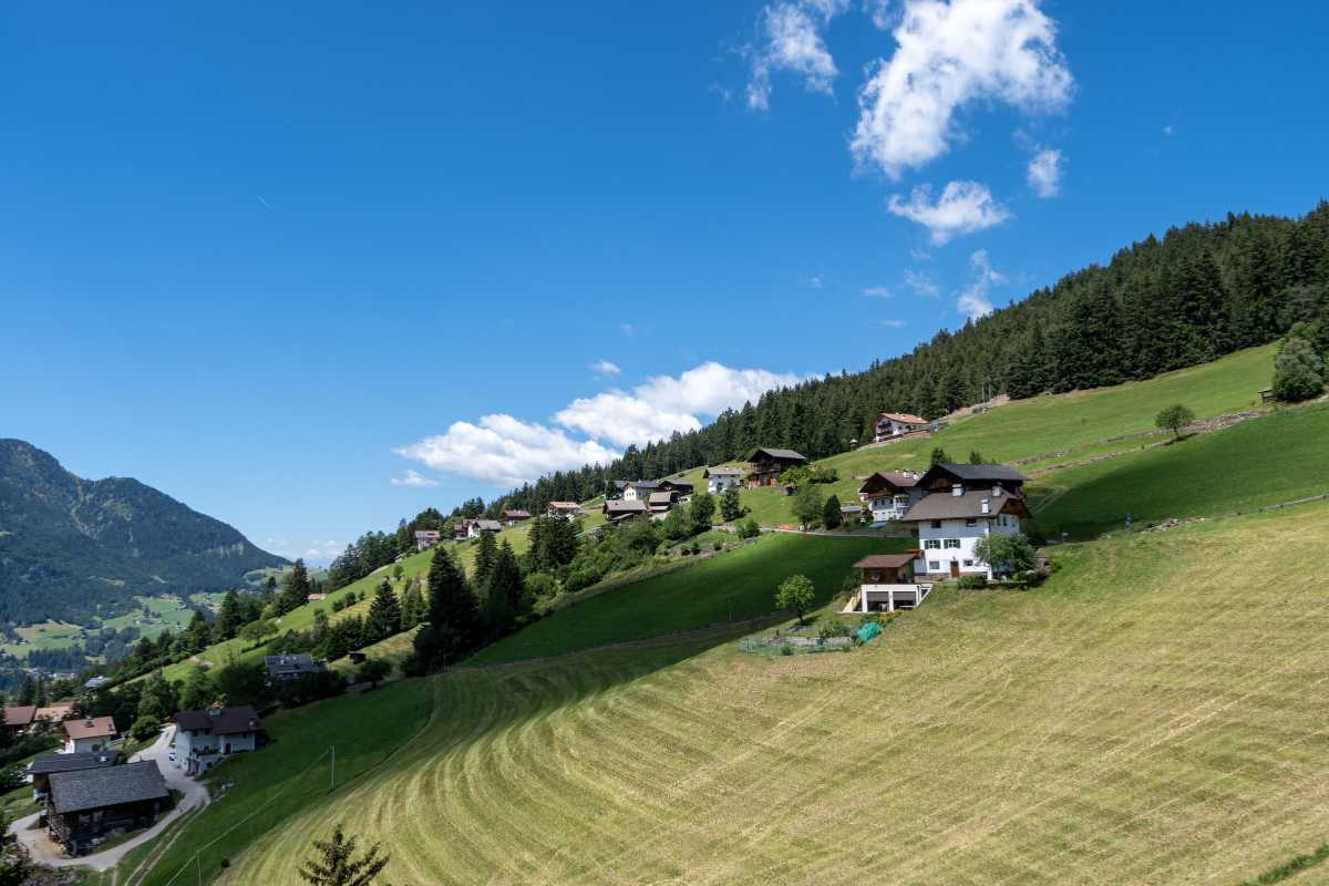 Gruppo di escursionisti sul Seceda con panorama sulle Odle, cielo sereno e prati verdi, Ortisei visibile in lontananza